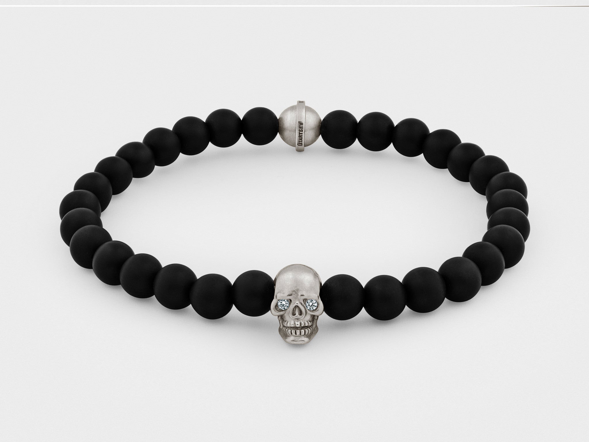 Bracelet tête de mort en argent avec yeux clairs et perle noire
